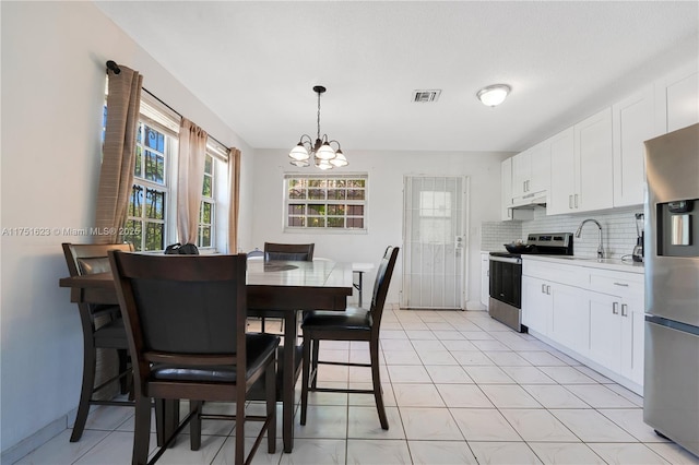 kitchen with tasteful backsplash, visible vents, appliances with stainless steel finishes, under cabinet range hood, and white cabinetry