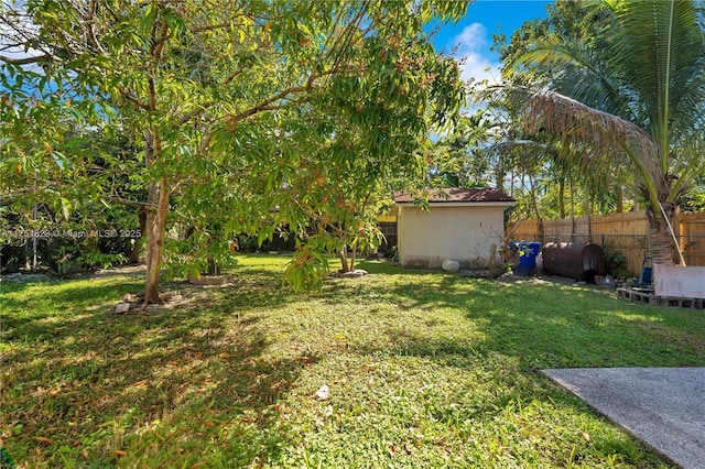 view of yard featuring an outbuilding, fence, and heating fuel