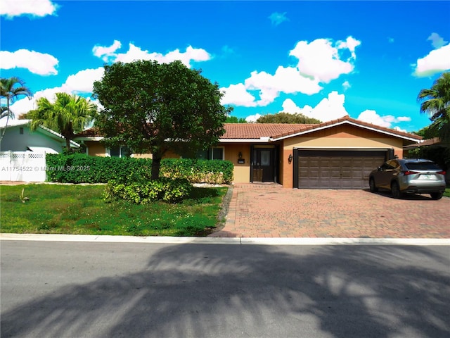 single story home featuring a garage, a tiled roof, decorative driveway, and stucco siding