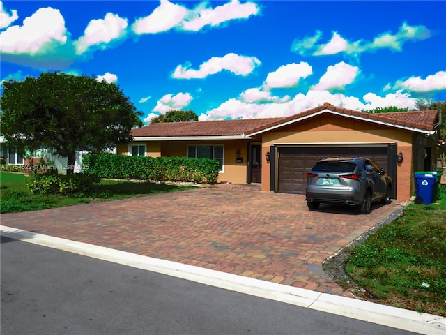 single story home with a garage, a tiled roof, decorative driveway, and stucco siding