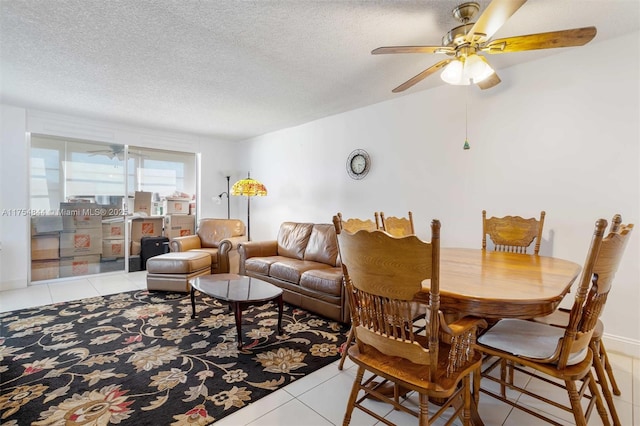 interior space with a ceiling fan, light tile patterned flooring, and a textured ceiling