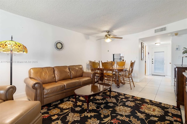 living room with a ceiling fan, visible vents, a textured ceiling, and light tile patterned floors