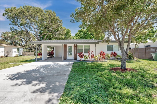 ranch-style house with driveway, an attached carport, a front yard, and fence