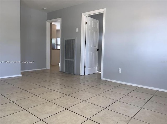 spare room featuring light tile patterned floors and baseboards