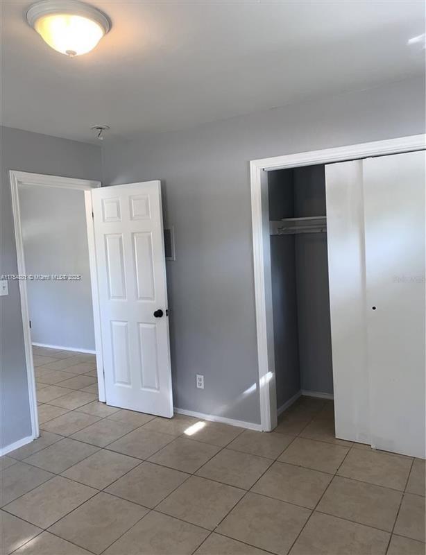 unfurnished bedroom with baseboards, a closet, and light tile patterned flooring