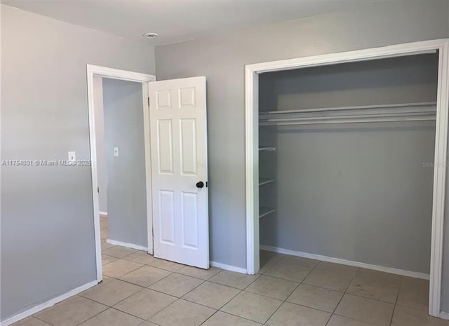 unfurnished bedroom featuring a closet, baseboards, and tile patterned floors