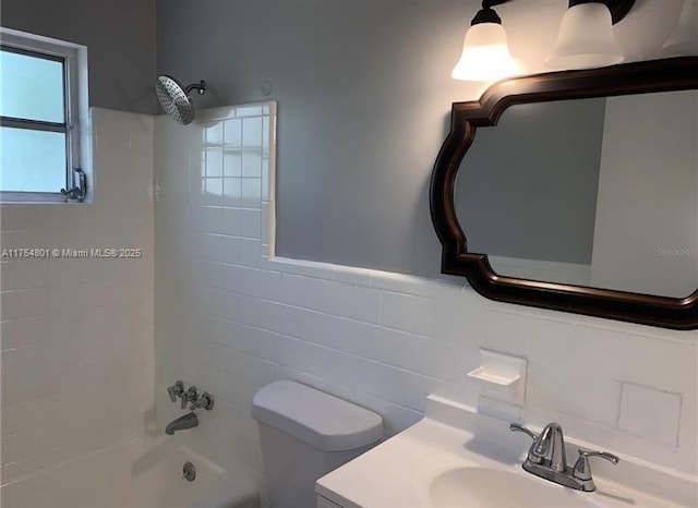 bathroom featuring toilet, vanity, tile walls, and shower / bathtub combination