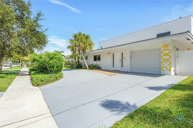 view of front of house with an attached garage, driveway, and stucco siding