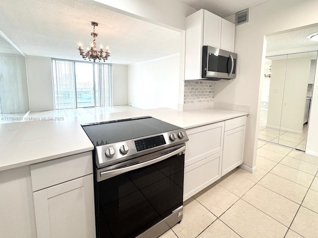 kitchen with tasteful backsplash, white cabinetry, stainless steel appliances, and light countertops