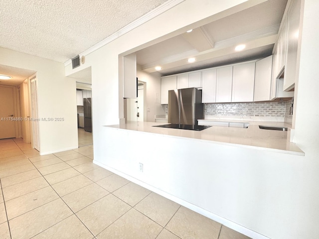 kitchen featuring light tile patterned floors, decorative backsplash, freestanding refrigerator, refrigerator, and light countertops