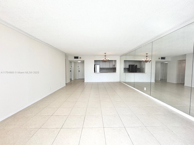 unfurnished living room featuring a textured ceiling, baseboards, a notable chandelier, and light tile patterned flooring