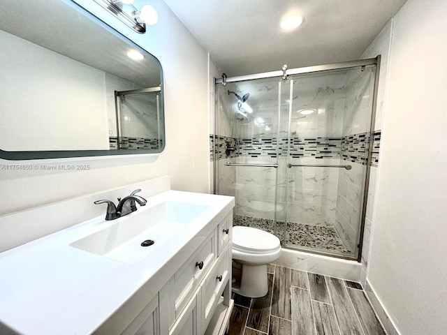 full bathroom with wood tiled floor, a shower stall, toilet, and vanity