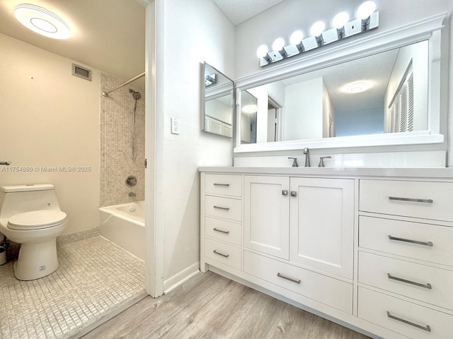 full bath featuring toilet, shower / bath combination, visible vents, vanity, and baseboards