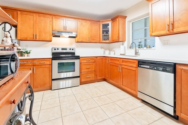 kitchen featuring light countertops, appliances with stainless steel finishes, a sink, and under cabinet range hood