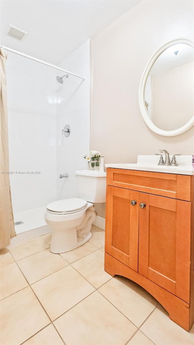 bathroom with visible vents, toilet, a tile shower, vanity, and tile patterned floors