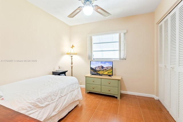 bedroom featuring a ceiling fan, a closet, light tile patterned flooring, and baseboards