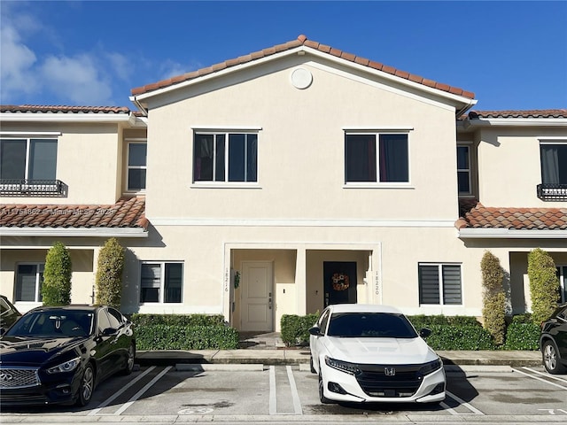 townhome / multi-family property featuring uncovered parking and stucco siding