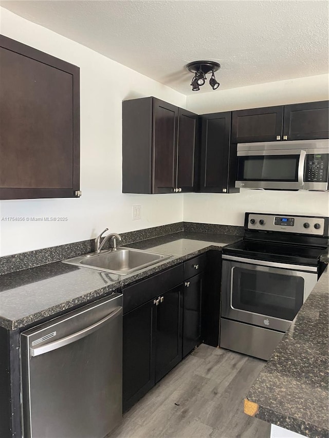 2217 NE 14th Ave, Wilton Manors, FL 33305 - kitchen with stainless steel appliances, light wood-type flooring, a sink, and a textured ceiling