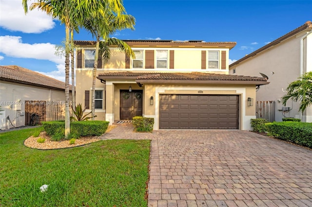 view of front of house with a tile roof, fence, decorative driveway, a front lawn, and stucco siding