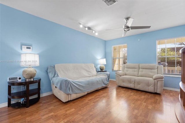 living area with a wealth of natural light, visible vents, and wood finished floors