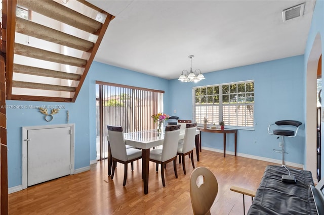 dining area featuring an inviting chandelier, baseboards, visible vents, and wood finished floors