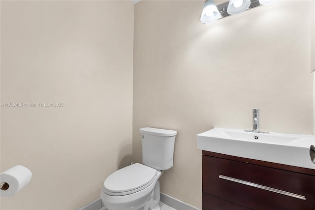 half bath featuring vanity, toilet, and baseboards