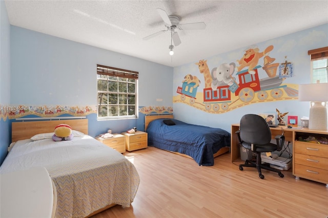 bedroom with light wood-type flooring, ceiling fan, and a textured ceiling