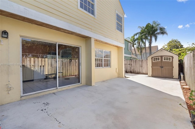 view of patio with a fenced backyard, an outdoor structure, and a storage unit