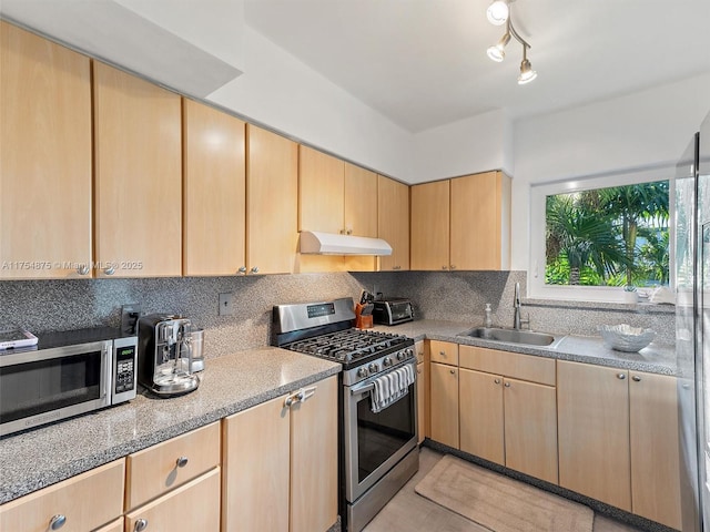 kitchen with decorative backsplash, appliances with stainless steel finishes, light brown cabinetry, under cabinet range hood, and a sink