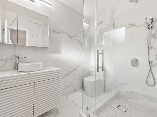 full bath featuring a marble finish shower and vanity