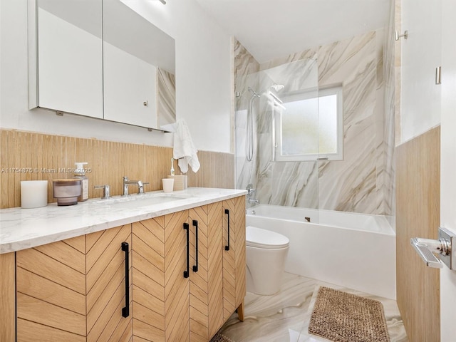 full bathroom featuring marble finish floor, tile walls, bathtub / shower combination, toilet, and vanity