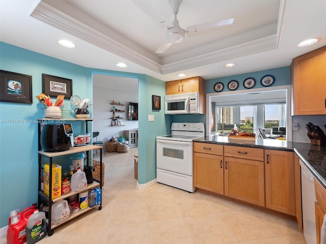 kitchen featuring dark countertops, white appliances, a tray ceiling, and ornamental molding