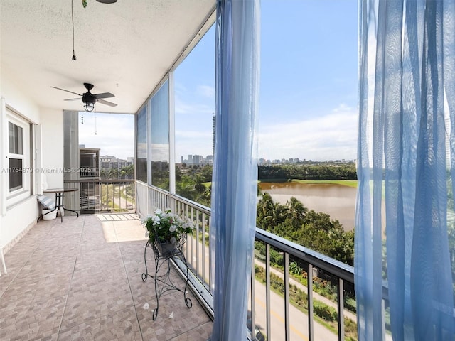 sunroom / solarium featuring a water view, a ceiling fan, and a city view