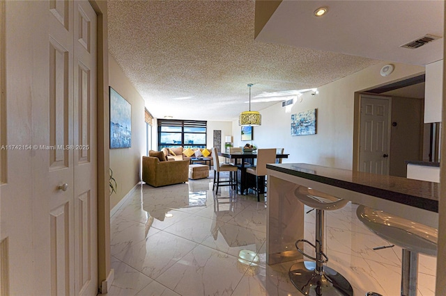 interior space with a textured ceiling, marble finish floor, and visible vents