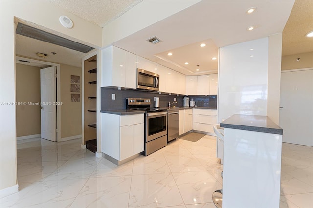 kitchen featuring visible vents, modern cabinets, marble finish floor, stainless steel appliances, and white cabinetry