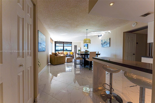 hall with baseboards, visible vents, a textured ceiling, and marble finish floor
