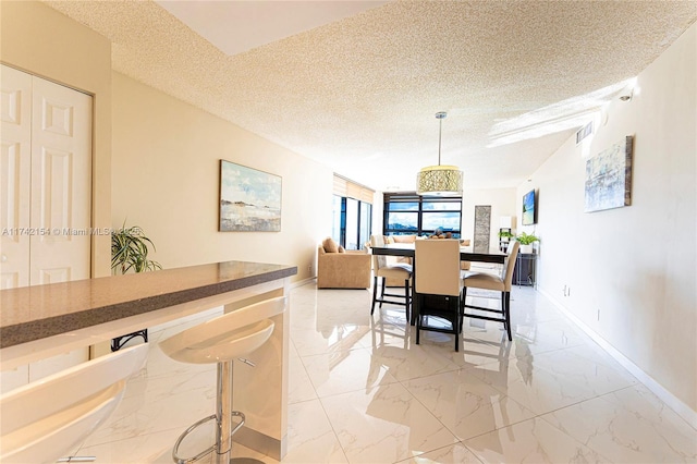 dining area featuring a textured ceiling, marble finish floor, visible vents, and baseboards