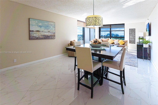 dining space featuring marble finish floor, baseboards, and a textured ceiling