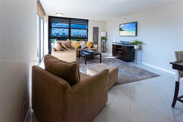 living area with marble finish floor, a textured ceiling, and baseboards