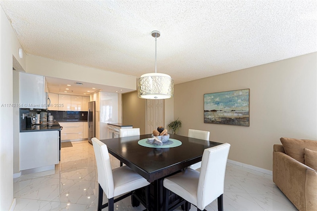 dining room with a textured ceiling, marble finish floor, and baseboards