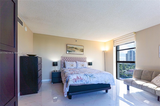 bedroom featuring a textured ceiling, marble finish floor, visible vents, and baseboards