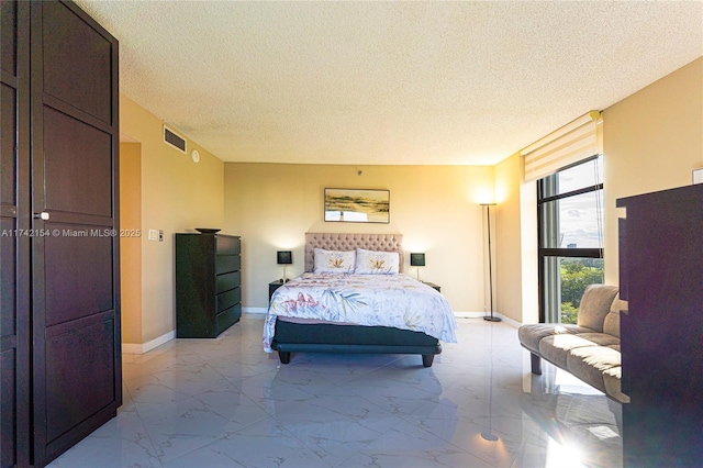 bedroom featuring marble finish floor, baseboards, visible vents, and a textured ceiling