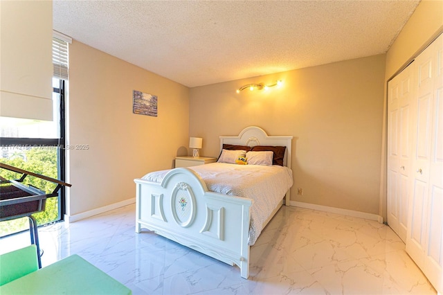 bedroom with a closet, marble finish floor, a textured ceiling, and baseboards