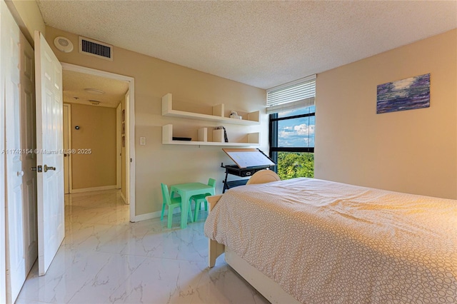 bedroom with marble finish floor, visible vents, baseboards, and a textured ceiling