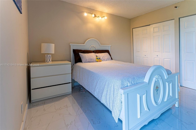 bedroom featuring marble finish floor, a textured ceiling, and baseboards