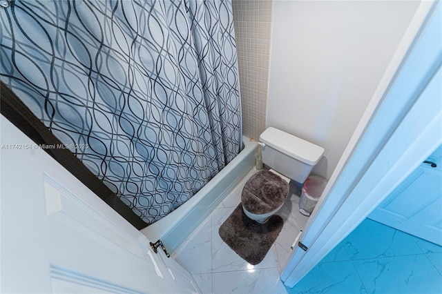 bathroom featuring toilet, marble finish floor, and shower / tub combo with curtain