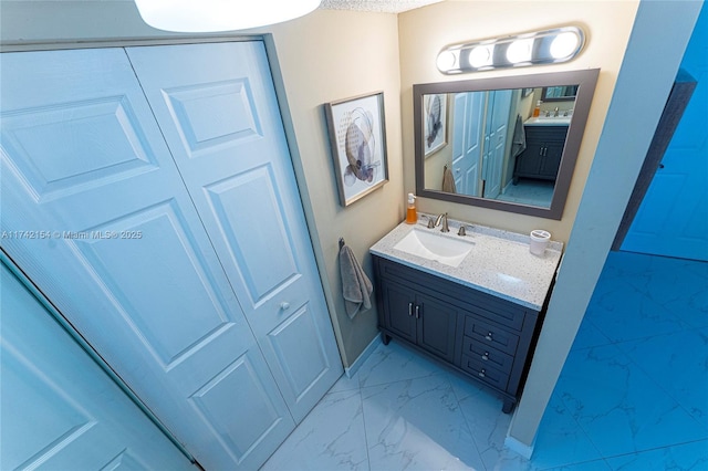 bathroom with marble finish floor, vanity, and baseboards