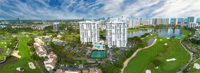 drone / aerial view featuring view of golf course, a water view, and a city view