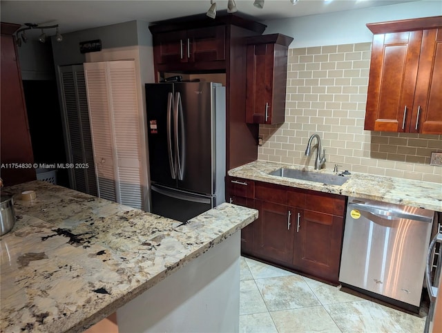 kitchen featuring appliances with stainless steel finishes, backsplash, a sink, and light stone counters