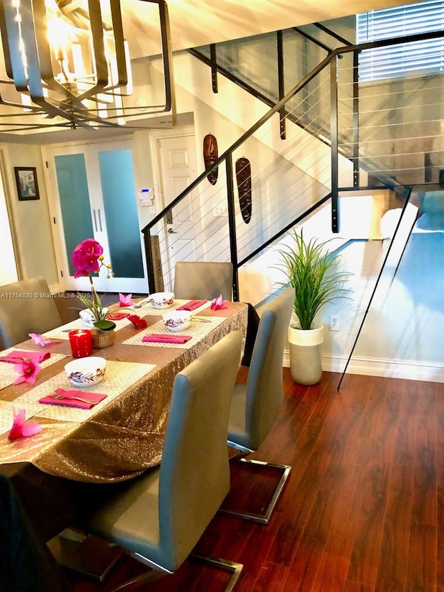 dining area with stairs, a notable chandelier, and wood finished floors